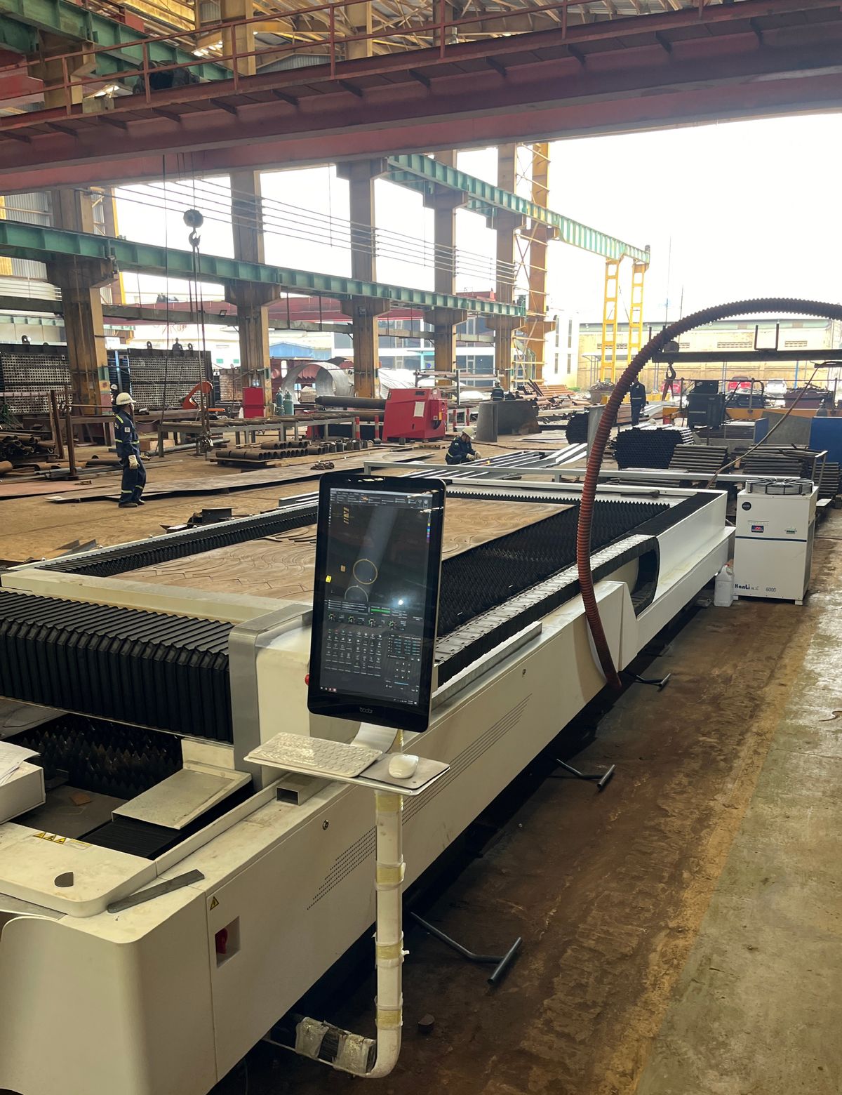 Offshore fabrication workshop with CNC cutting bed, overhead cranes and steel stock